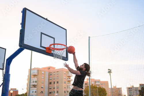 Afro-Latino man plays basketball and dunks the ball into a basket © Cristian Blázquez