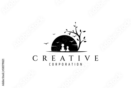 Vector logo design where a boy is sitting with his little sister in the shade of a beautiful tree overlooking the sunset with birds in the sky.
