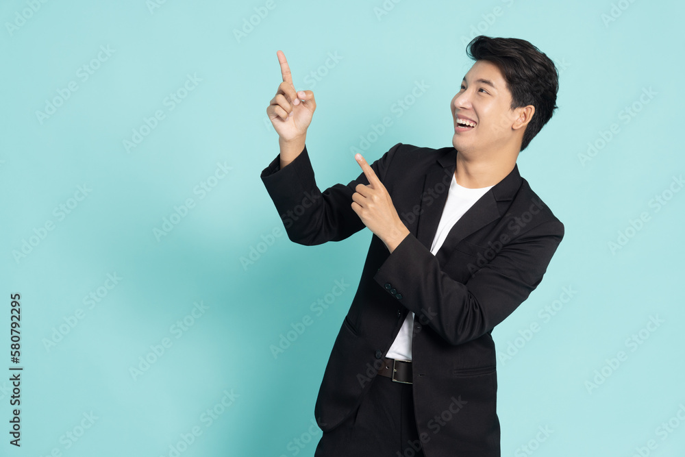 Young Asian businessman smiling and pointing to empty copy space isolated on green background Young Asian businessman smiling and pointing to empty copy space isolated on green background