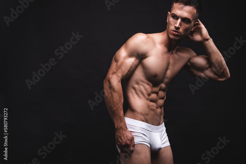 Handsome young man in a white underwear posing over gray background. Perfect body and skin. Studio shot.