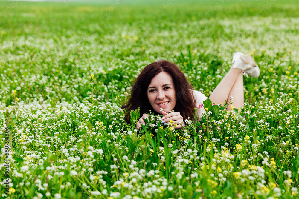 a beautiful woman lies in a green clearing in nature