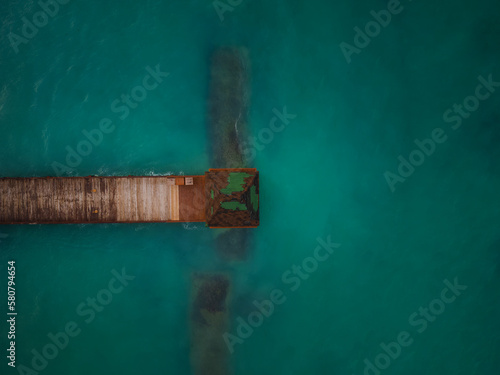 Shooting from a drone. Pier on the sea. Dark turquoise water and algae. Climate change, global warming, environmental protection, ecology. © Anton