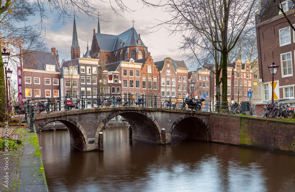 Naklejka premium Beautiful old houses on the city embankment of Amsterdam at sunset.