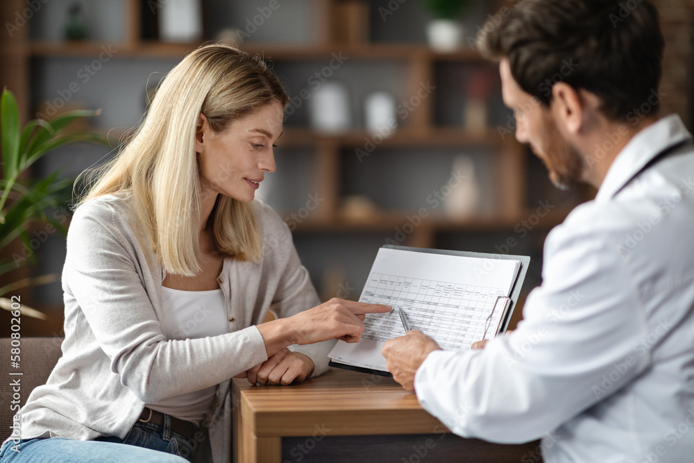 Female Patient Discussing Blood Test Results With Doctor During Meeting In Office Female Patient Discussing Blood Test Results With Doctor During Meeting In Office
