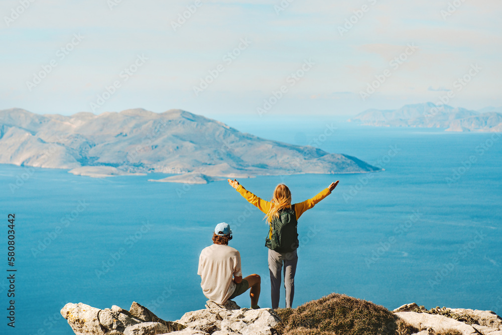 Couple travelers hiking in Greece together outdoor travel lifestyle active summer vacations man and woman on Akramitis mountain top enjoying aerial sea view explore Rhodes island - obrazy, fototapety, plakaty 