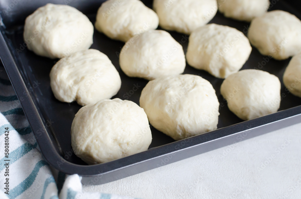 The process of forming buns, the balls are laid out in a baking dish. Preparation of pampushky (Pampushky), traditional Ukrainian buns for borsch. Homemade baking. Horizontal orientation The process of forming buns, the balls are laid out in a baking dish. Preparation of pampushky (Pampushky), traditional Ukrainian buns for borsch. Homemade baking. Horizontal orientation