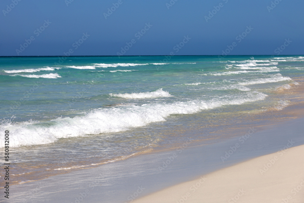 Ocean beach with white sand, view to azure waves and clear sky. Background for holidays on a paradise nature