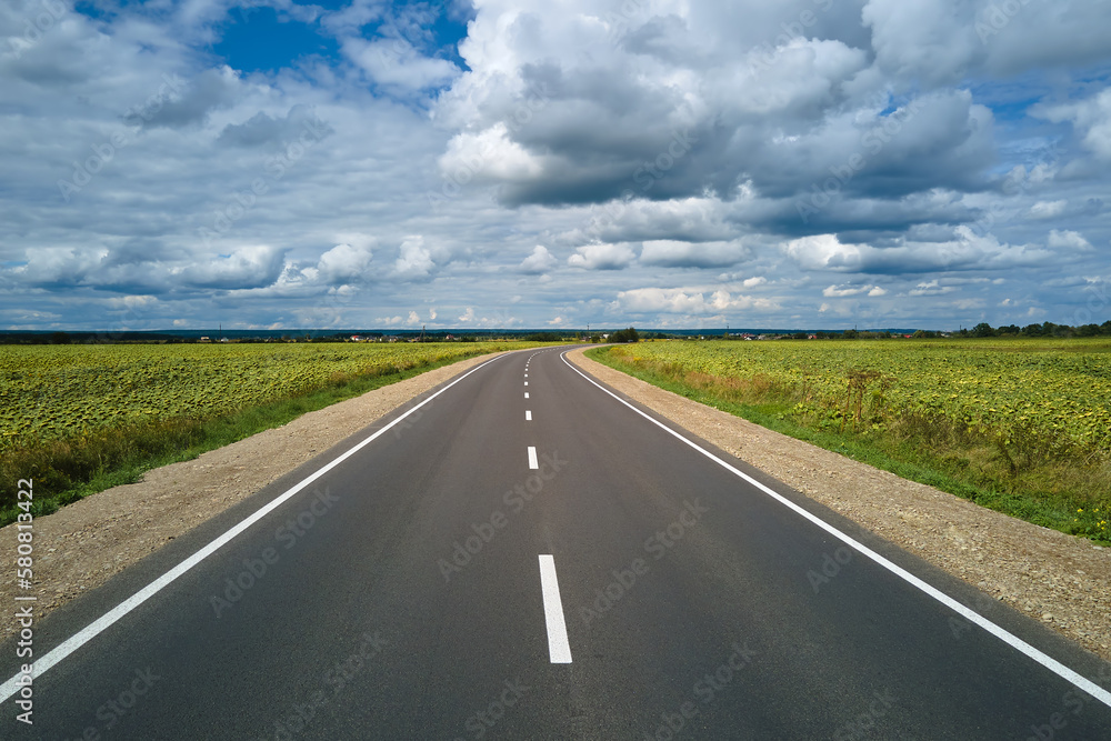 Aerial view of empty intercity road between green agricultural fields. Top view from drone of highway roadway Aerial view of empty intercity road between green agricultural fields. Top view from drone of highway roadway