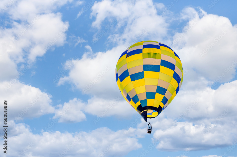 Colorful hot air balloon flying over blue sky with white clouds Colorful hot air balloon flying over blue sky with white clouds