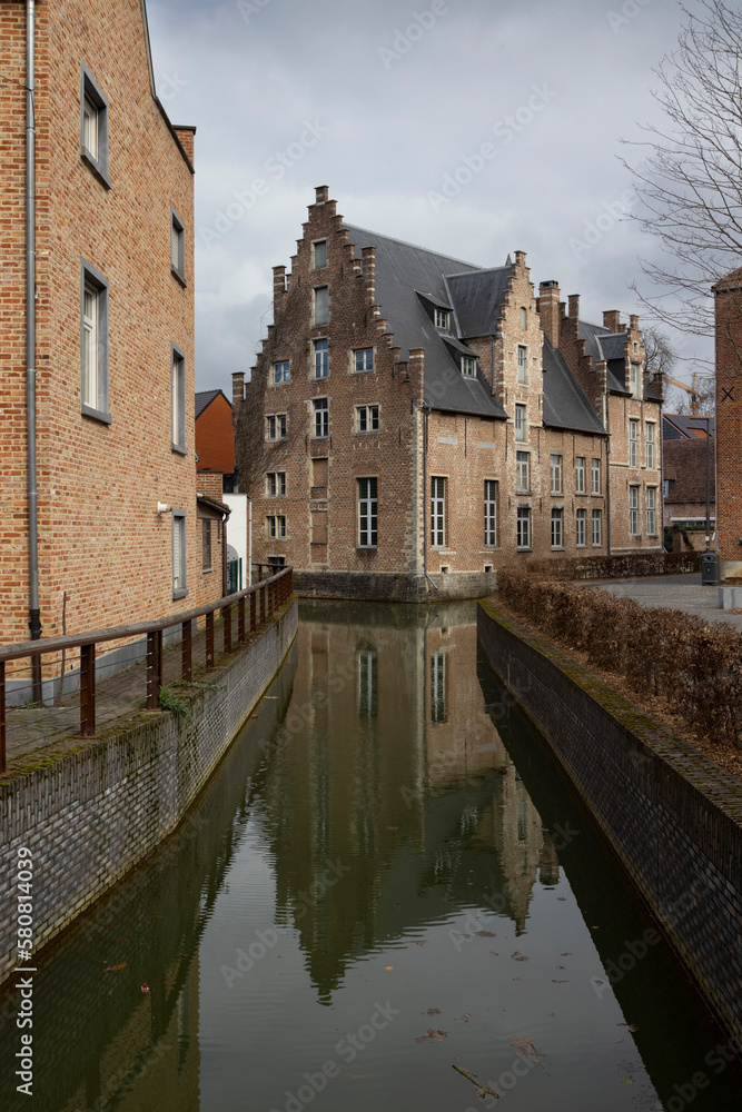 The Demer river and the 16th century building 'Het Spijker' (also known as Hof van Tongerlo) in the Flemish Brabant city of Diest, in Belgium. Winter view with reflections in the water.