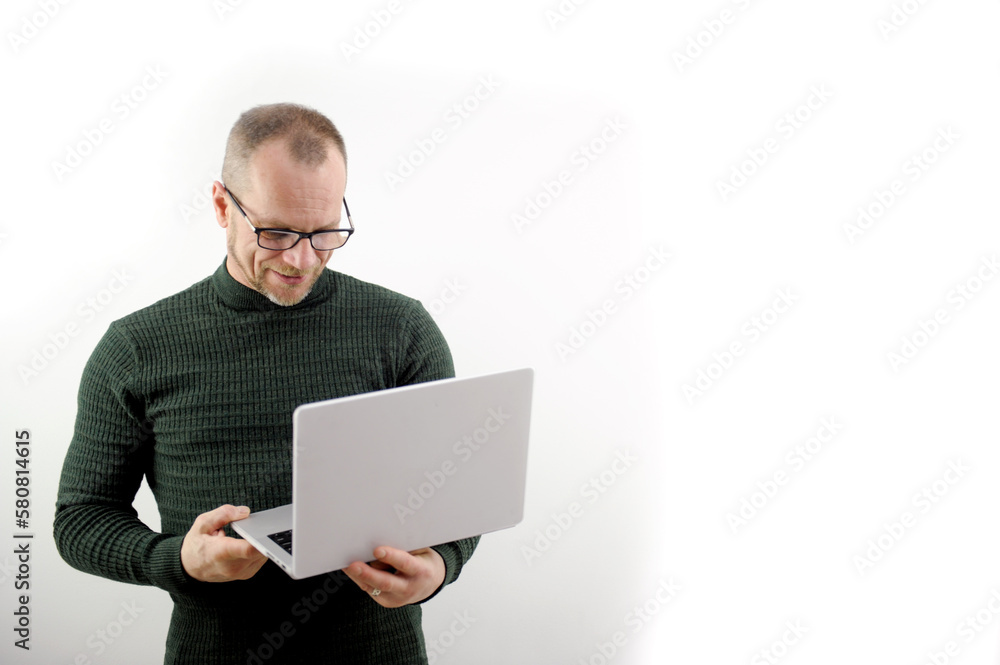Focused man in glasses using a laptop, typing on the keyboard, writing an email or message, chatting, shopping, a successful freelancer working online on a computer stands on a white background Focused man in glasses using a laptop, typing on the keyboard, writing an email or message, chatting, shopping, a successful freelancer working online on a computer stands on a white background