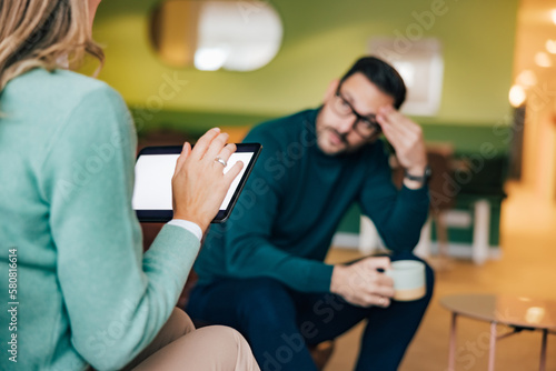 Adult business male and female solving a problem  working over the digital tablet  sitting on the couch.