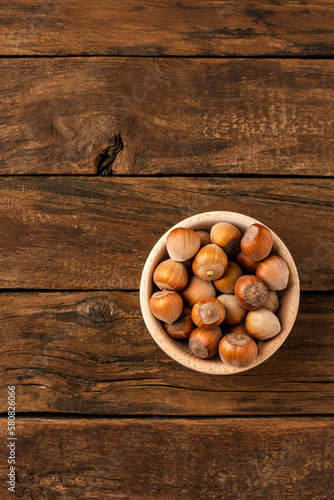 Fresh hazelnuts in bowl on wooden background with copyspace. Top view