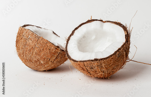 Open coconut. Two halves, cut pieces of coco nut with brown shell and white flesh