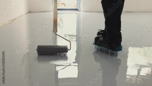 Epoxy flooring is made up of multiple layers of epoxy that is applied to a surface by a professional worker photo