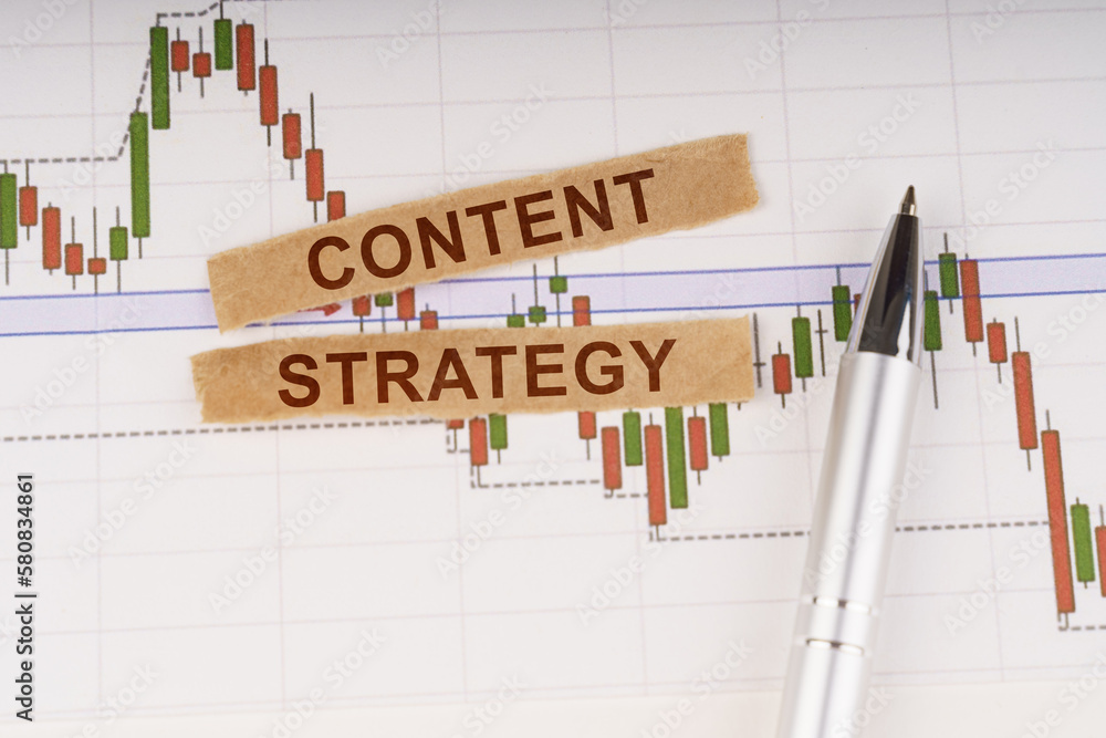 On the chart of business quotes lies a pen and torn paper with the inscription - CONTENT STRATEGY On the chart of business quotes lies a pen and torn paper with the inscription - CONTENT STRATEGY
