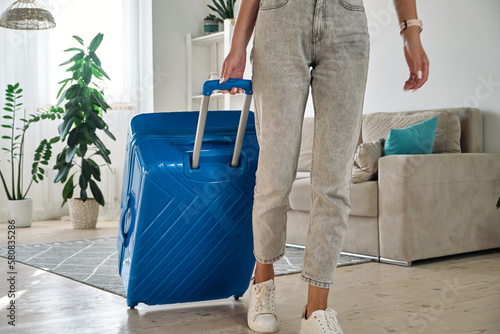 Unrecognizable woman leaving home with a suitcase going on a trip or vacation