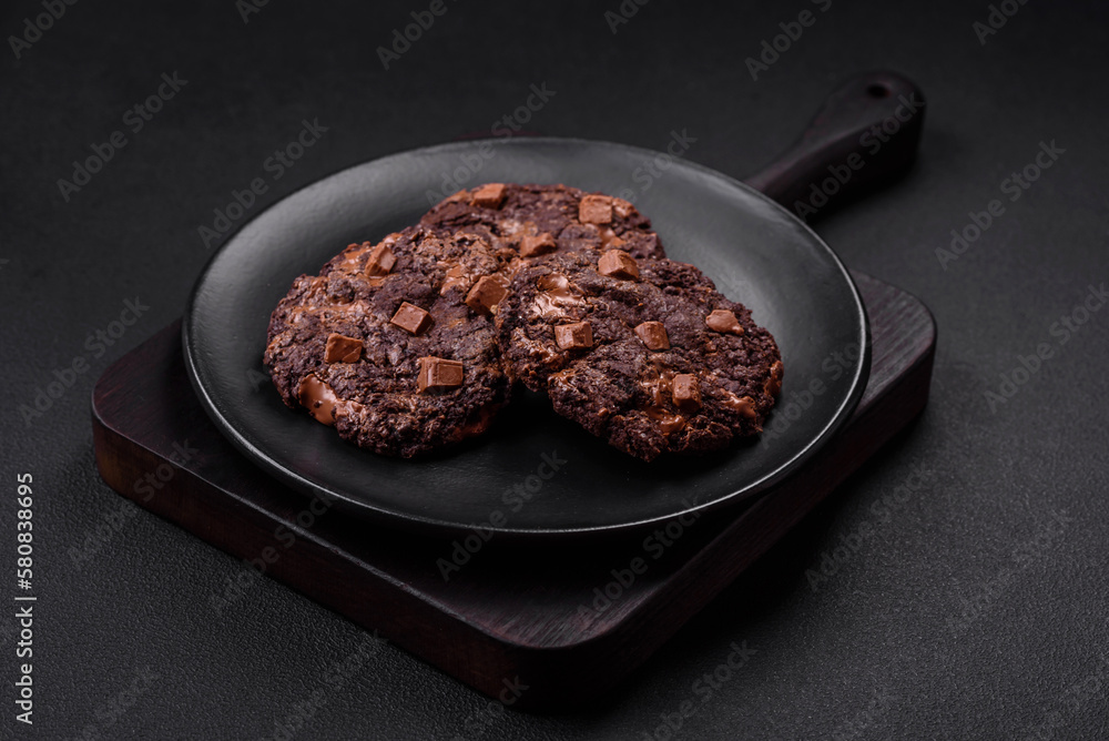 Delicious fresh oatmeal round cookies with chocolate on a black ceramic plate Delicious fresh oatmeal round cookies with chocolate on a black ceramic plate