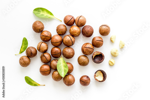 Pile of raw macadamia nuts with leaves. Healthy protein snack background