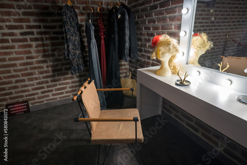 Interior of a back stage or offstage female dressing room consist of a chair, wig, mirror, wardrobe and make up stuff photo