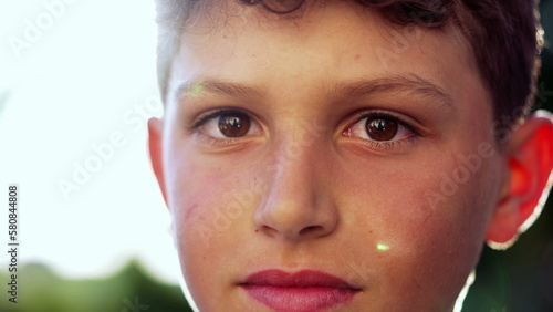 Portrait of a preteen male child close up face standing outside in nature. Young boy kid