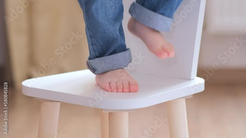 Little charming childrens feet stomp on the chair