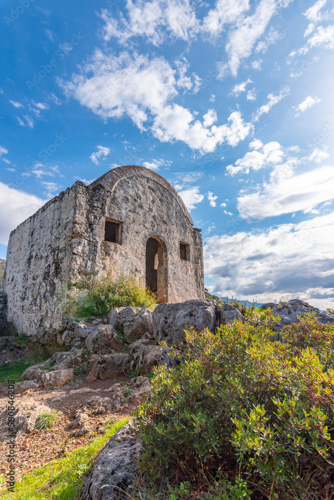 View of Kayakoy Fethiye with abandoned buildings and clouds on blue sky and green grass