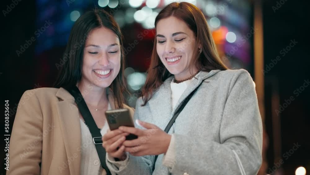 Video of two beautiful friends talking and using smartphone while walking on the city street with shopping bag. Video of two beautiful friends talking and using smartphone while walking on the city street with shopping bag.
