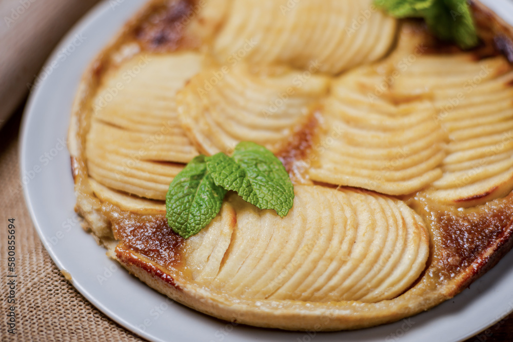 French apple pie on its crispy puff base are sliced juicy apples mixed with brown sugar, nutmeg and other spices. Decorated with mint leaves. French apple pie on its crispy puff base are sliced juicy apples mixed with brown sugar, nutmeg and other spices. Decorated with mint leaves.