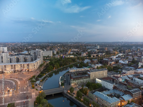 City aerial view on bridge across river Lopan, park, embankment and streets in evening lights in spring Kharkiv, Ukraine