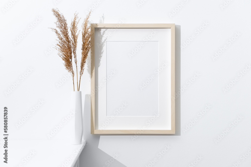 Wooden artwork frame mockup on white wall with dry grass decoration Wooden artwork frame mockup on white wall with dry grass decoration