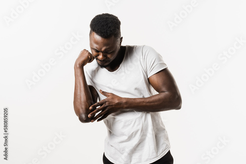 Elbow injury causing pain, swelling, stiffness, and limited movement. Fractures, dislocations, sprains, and tennis elbow. Elbow injury of african american man isolated on white background.