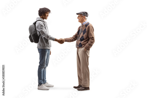 Full length profile shot of an african american male student and a caucasian senior man shaking hands
