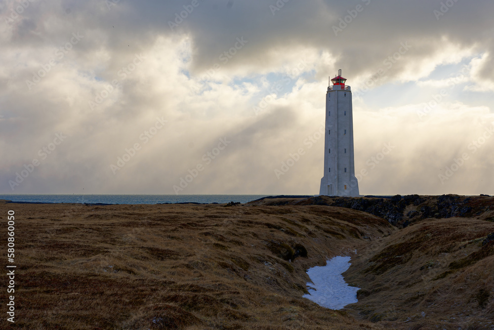 Phare blanc et rouge islandais de la région de Hellisandur au coucher du soleil 