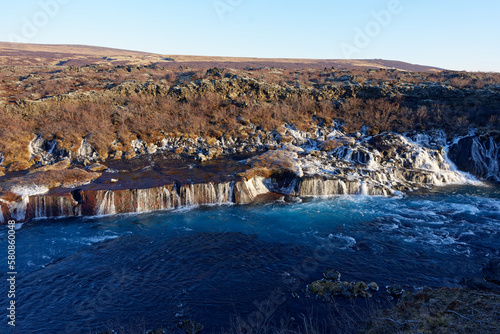 magnifique cascade gelé avec une eau sortant directement de la roche avec eau de rivière turquoise sur une montagne ensoleillé d'Islande