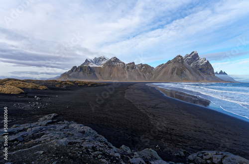 montagne d'Islande enneige au bord d'une plage de sable noir prise au grand angle donnant une perspectivement d'immensité et de solitude