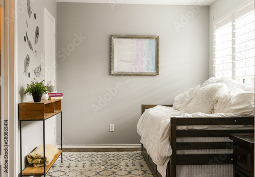 Small neutral bedroom with single bed, rug, empty, natural light