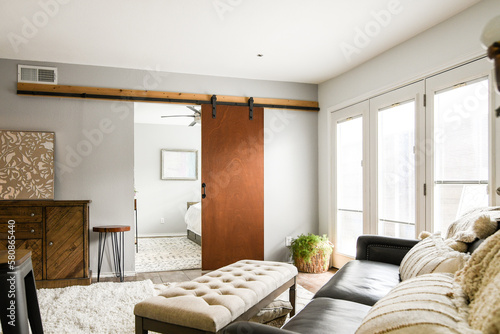 View from living room into to neutral bedroom with single bed, rug, empty, natural light