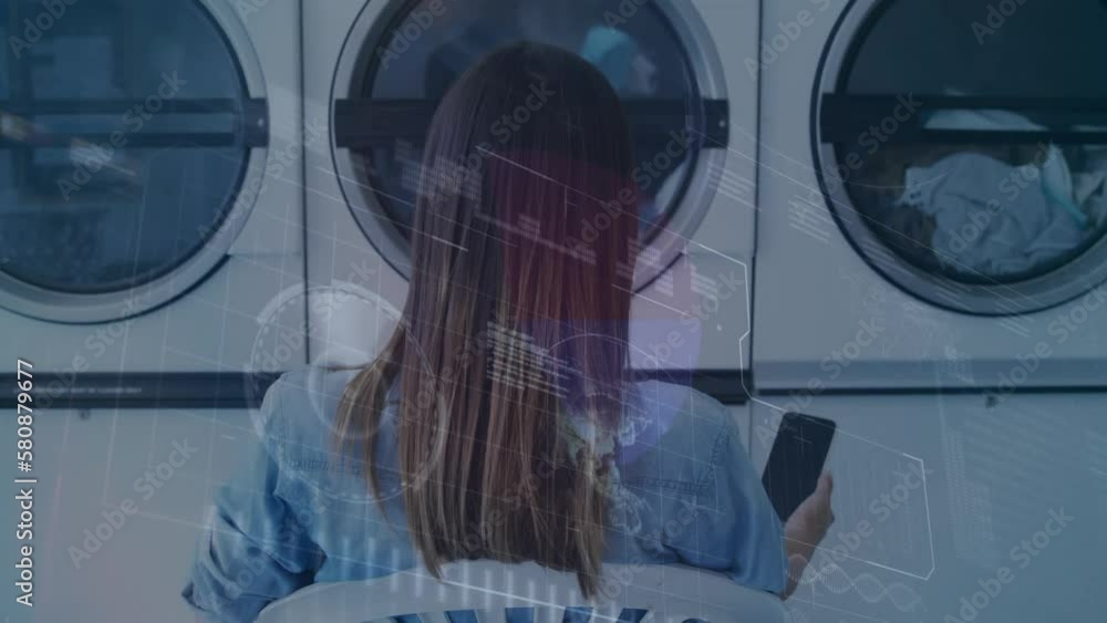 Animation of financial data processing over woman using smartphone in laundrette Animation of financial data processing over woman using smartphone in laundrette