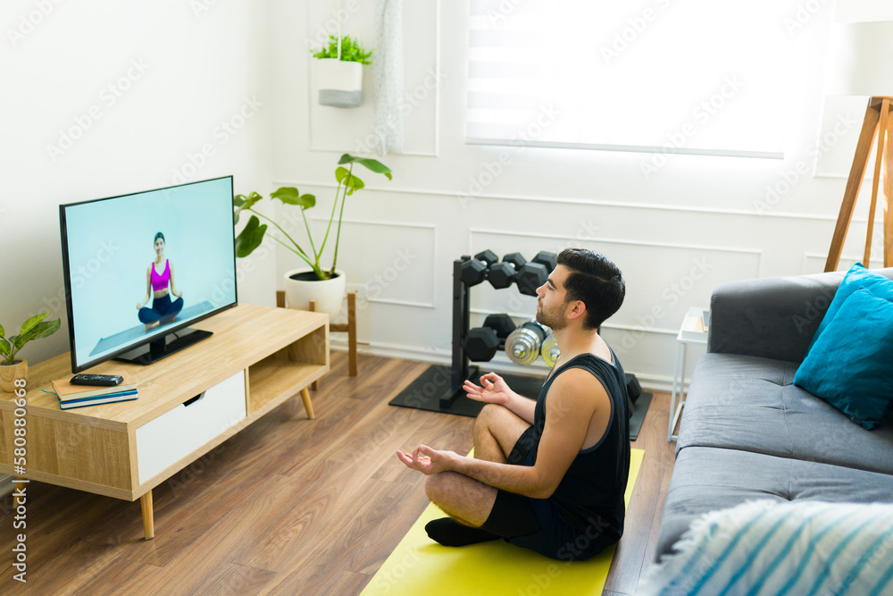 Relaxed latin man watching a meditation video at home Relaxed latin man watching a meditation video at home