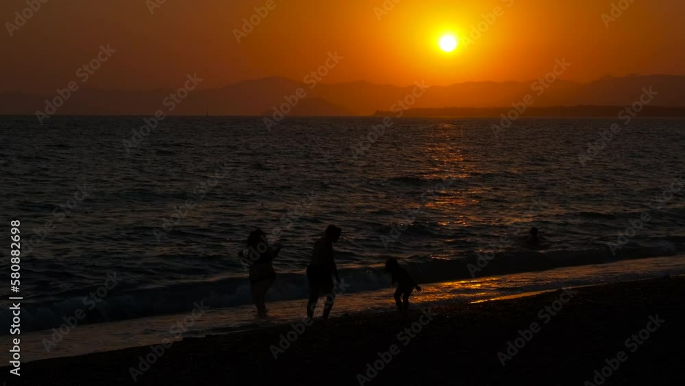 Tourist with child silhouette in nightfall sea. A view of sea waterfront with tourists and child silhouette in evening. A concept of sunny summer time on shore. Tourist with child silhouette in nightfall sea. A view of sea waterfront with tourists and child silhouette in evening. A concept of sunny summer time on shore.