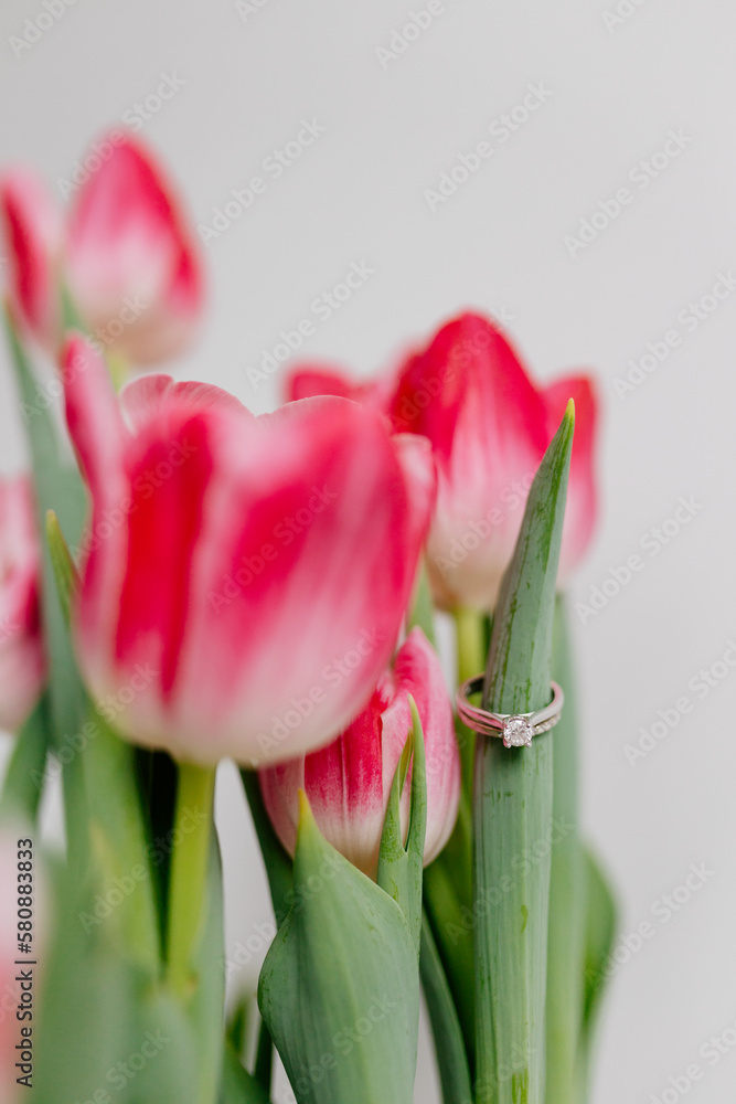 Naklejka premium Pink tulips and engagement rings with diamonds on white background. Background for Valentine's Day. Gift for Mother's Day, international Women's Day, March 8th. Spring Mock ups. Space for text