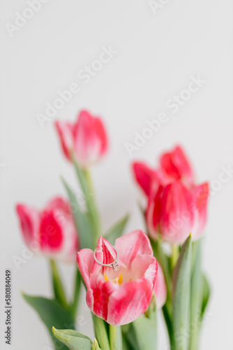 Pink tulips and engagement rings with diamonds on white background. Background for Valentine's Day. Gift for Mother's Day, international Women's Day, March 8th. Spring Mock ups. Space for text