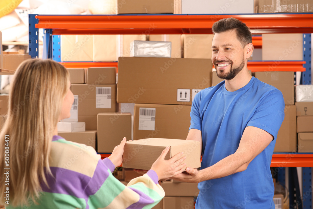 Worker giving parcel to woman at post office Worker giving parcel to woman at post office