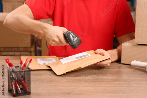 Post office worker with scanner reading parcel barcode at counter, closeup