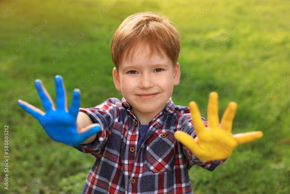 Little boy with hands painted in Ukrainian flag colors outdoors. Love Ukraine concept Little boy with hands painted in Ukrainian flag colors outdoors. Love Ukraine concept