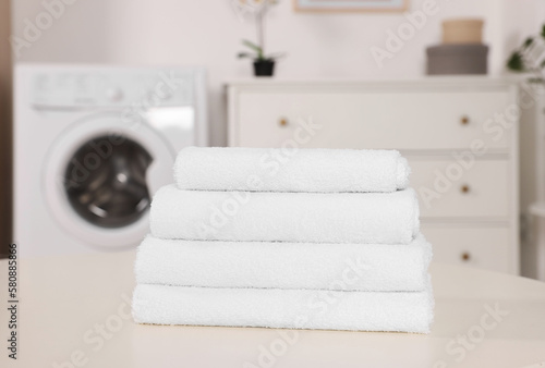 Stack of folded towels on white table in laundry room