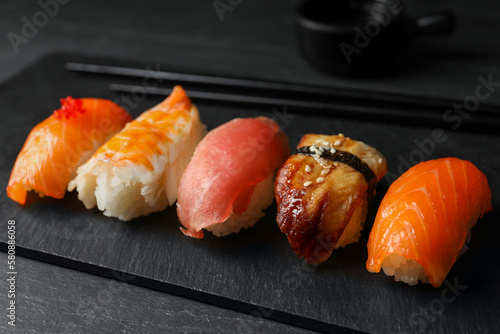 Plate with delicious nigiri sushi on black table
