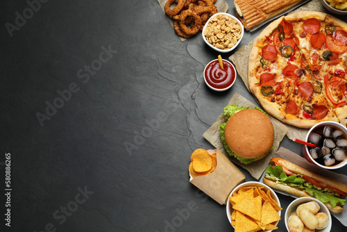 Pizza, burger and other fast food on black table, flat lay with space for text