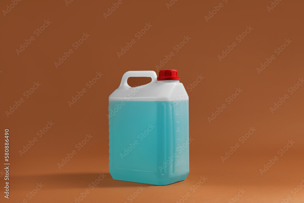 Plastic canister with blue liquid on brown background